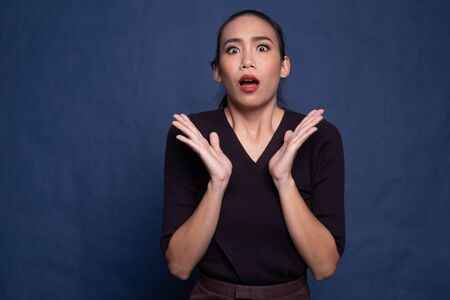 Shocked young Asian woman on blue backgroundの写真素材