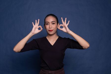 Asian woman show double OK hand sign  and smile on blue background