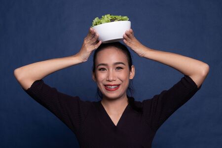 Healthy Asian woman with salad on blue backgroundの写真素材