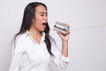 Young Asian woman shout with tin can phone on white backgroundの写真素材