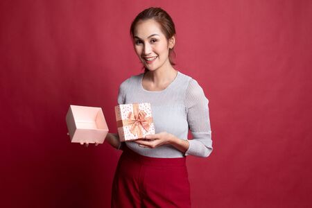 Young Asian woman open a golden gift box on red backgroundの写真素材