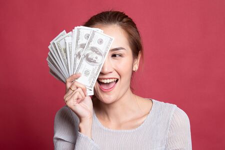 Portrait of  young asian woman  showing bunch of money banknotes on red background