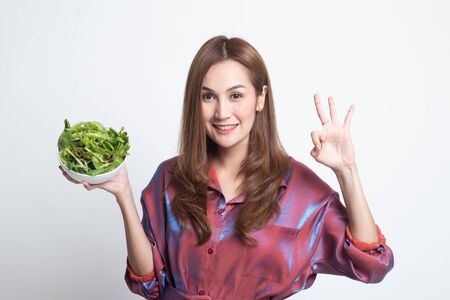 Healthy Asian woman show OK with salad on white background