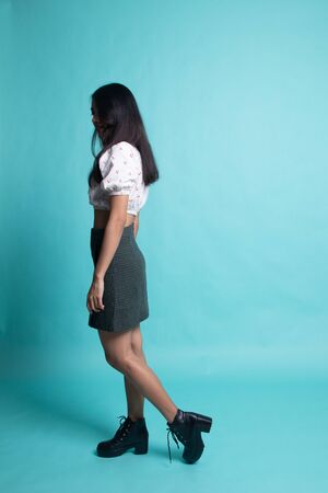 Full body of beautiful young asian woman walking on cyan color backgroundの写真素材
