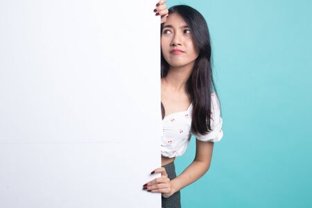 Young Asian woman with blank sign on cyan color backgroundの写真素材