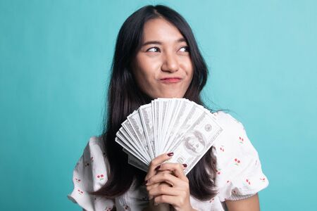 Portrait of  young asian woman  showing bunch of money banknotes on cyan color backgroundの写真素材