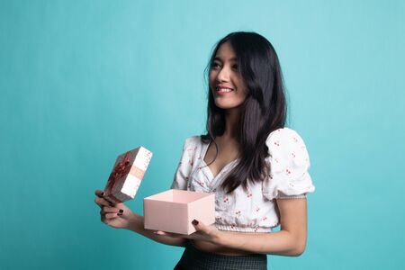 Young Asian woman open a gift box on cyan color backgroundの写真素材