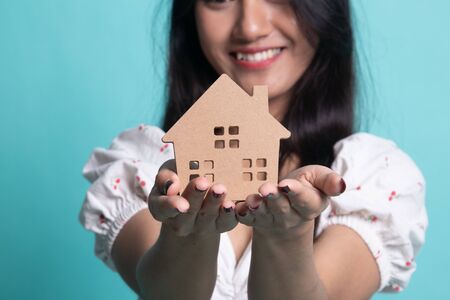 Happy young asian woman with house model on cyan color backgroundの写真素材