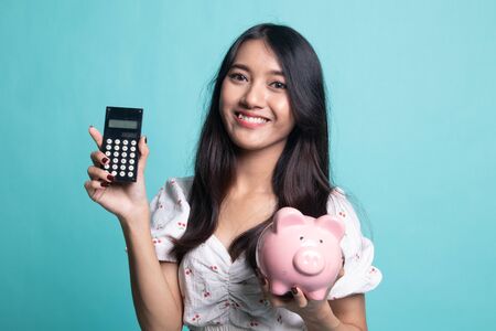 Asian woman with calculator and piggy bank on cyan color backgroundの写真素材