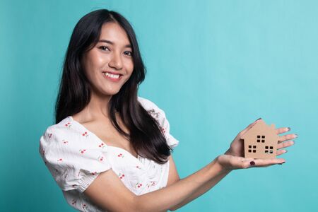 Happy young asian woman with house model on cyan color backgroundの写真素材