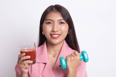 Young healthy Asian woman with dumbbell and  tomato juice on white background.の写真素材
