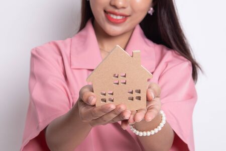 Happy young asian woman with house model on white background.の写真素材