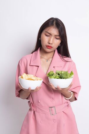 Young Asian woman with potato chips and salad on white background.の写真素材