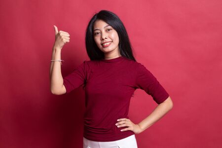 Young Asian woman show thumbs up on red background.の写真素材