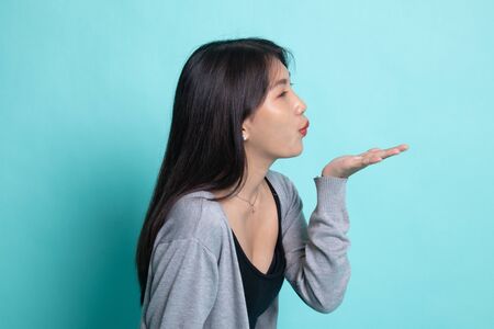 Beautiful young Asian woman blow a kiss on cyan background.の写真素材