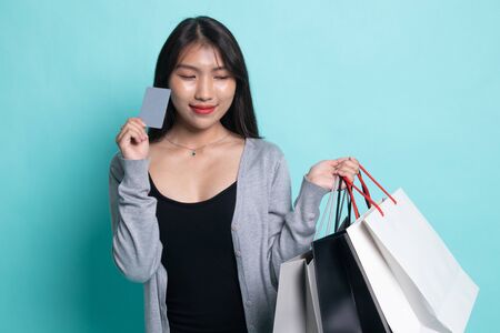 Young Asian woman with shopping bag and blank card on cyan background.の写真素材
