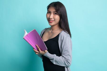 Young Asian woman read a book on cyan background.の写真素材