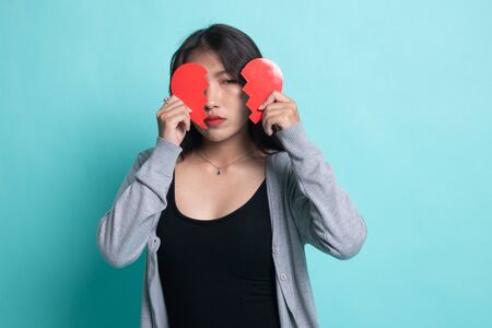 Beautiful young Asian woman with broken heart on cyan background.の写真素材