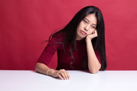 Asian girl is getting bore on red background.の写真素材