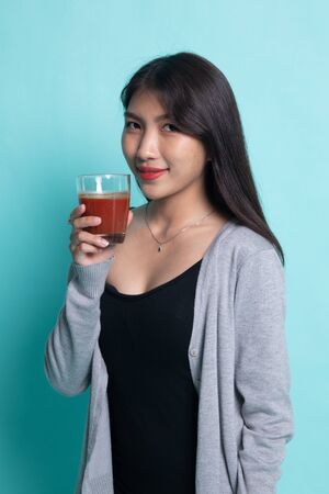 Young Asian woman drink tomato juice on cyan background.の写真素材