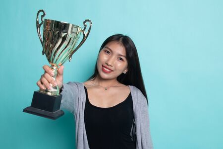 Successful young asian woman holding a trophy on cyan background.の写真素材