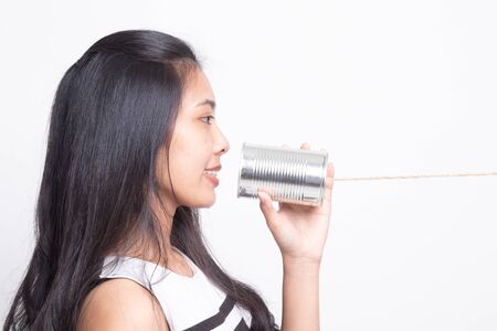 Young Asian woman with tin can phone on white background