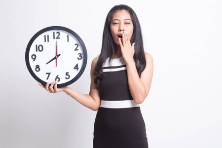 Sleepy young Asian woman with a clock in the morning on white background