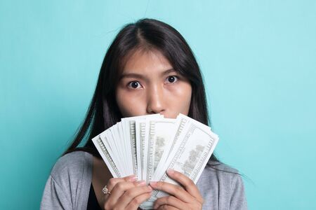 Portrait of  young asian woman  showing bunch of money banknotes on cyan background.の写真素材