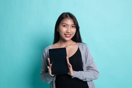 Young Asian woman with a computer tablet on cyan background.の写真素材