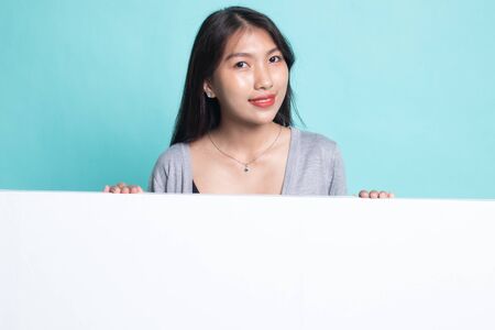 Young Asian woman with blank sign on cyan background.の写真素材