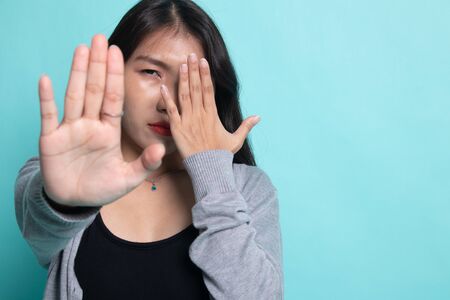 Young Asian woman hide her  face on cyan background.の写真素材