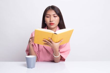 Young Asian woman read a book with cup of coffee on white background.の写真素材