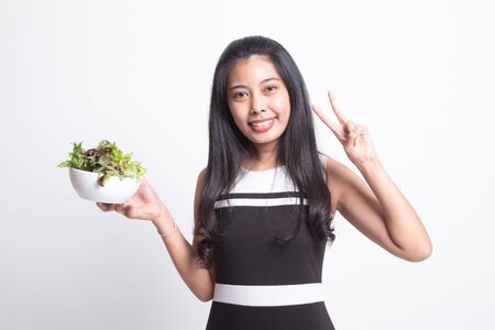 Healthy Asian woman show victory sign with salad on white backgroundの写真素材