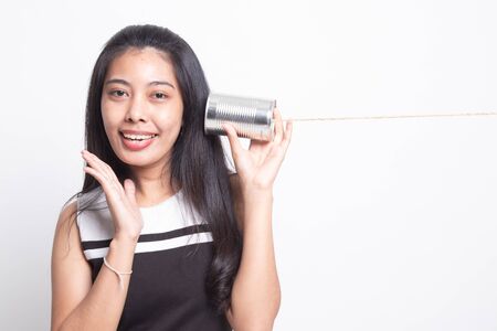 Happy Young Asian woman listen with tin can phone on white backgroundの写真素材