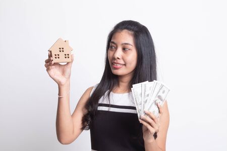 Happy young asian woman with house model and bunch of money banknotes on white backgroundの写真素材