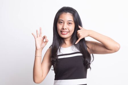 Young Asian woman show with phone gesture and OK sign on white backgroundの写真素材