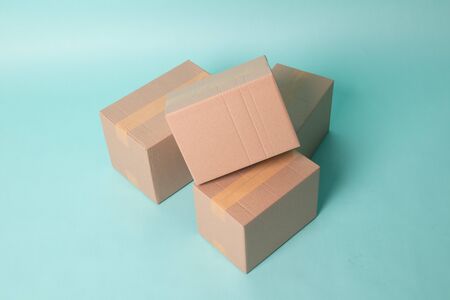 Pile of three  taped up  cardboard boxes on cyan background
