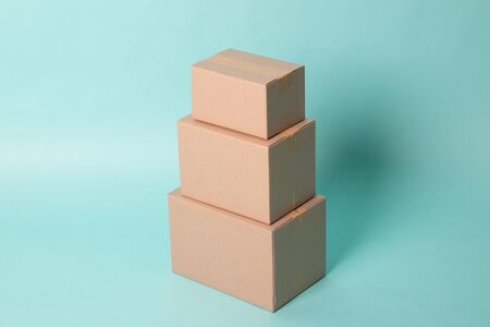 Pile of various size taped up  cardboard boxes on cyan backgroundの写真素材