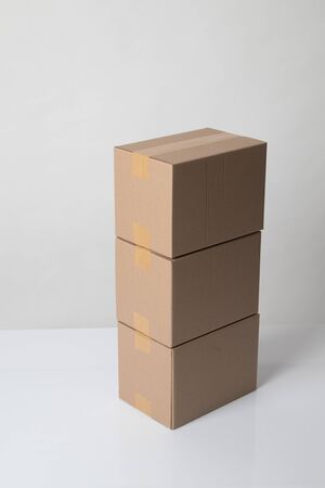 Pile of three  taped up  cardboard boxes on white backgroundの写真素材
