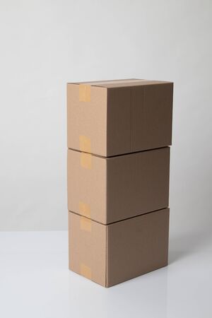 Pile of three  taped up  cardboard boxes on white backgroundの写真素材