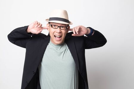 adult asian man  block both ears with finger on white backgroundの写真素材