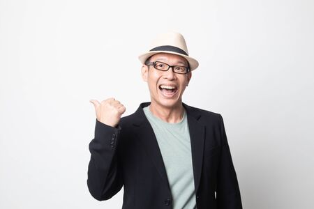 adult asian man  smile and point to copy space with her thumb on white backgroundの写真素材