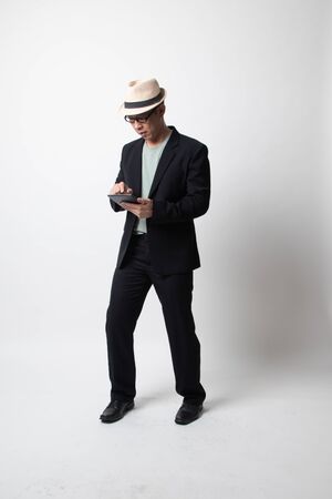 Full body of an adult asian man with a computer tablet on white backgroundの写真素材