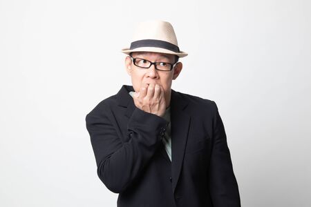Unsure hesitant nervous adult asian man  biting his fingernails on white backgroundの写真素材