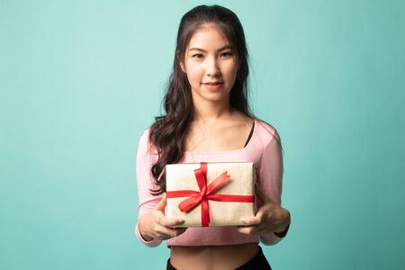 Young Asian woman with a gift box on cyan backgroundの写真素材