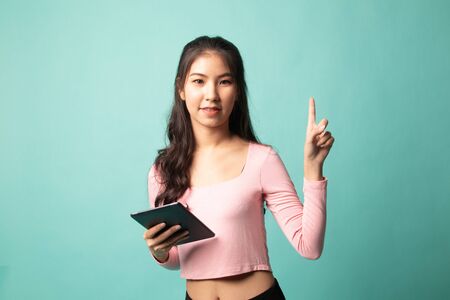 Young Asian woman with a computer tablet on cyan backgroundの写真素材