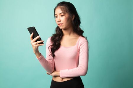 Young Asian woman with mobile phone on cyan backgroundの写真素材