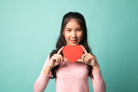 Asian woman with red heart on cyan backgroundの写真素材