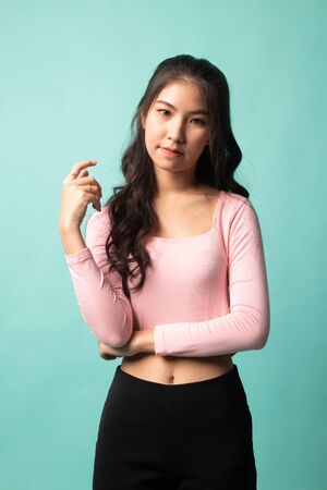 Portrait of beautiful young Asian woman on cyan backgroundの写真素材
