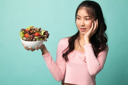 Healthy Asian woman with salad on cyan backgroundの写真素材